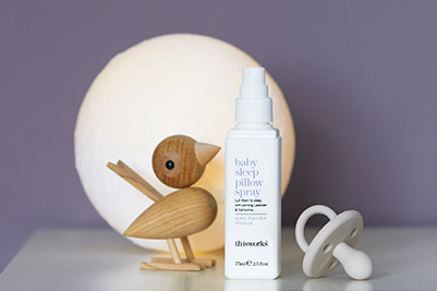 a bottle of baby sleep pillow spray next to a woden toy bird and a pacifier