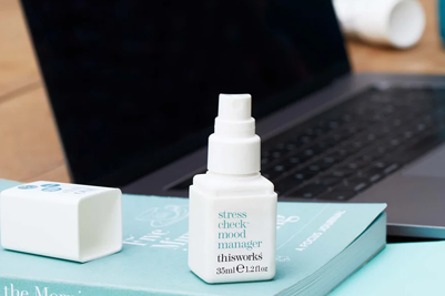 a bottle of stress check mood manager sits next to a laptop