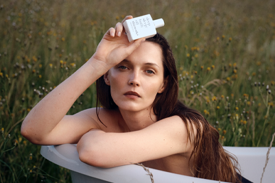 A person holds a bottle of deep sleep bath oil to their face