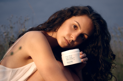 A person holds a jar of deep sleep body whip to their face