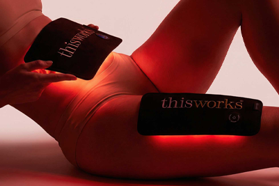 A person holds a red light body wrap to their stomach and one to their leg