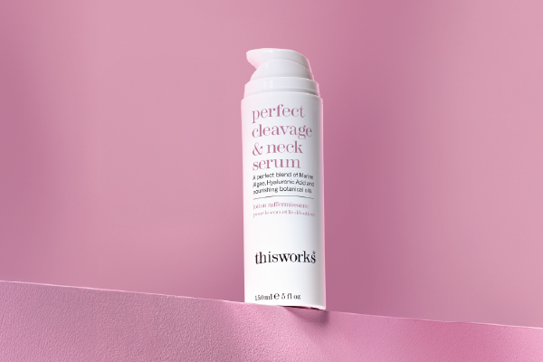 A bottle of thisworks perfect cleavage & neck serum centered against a pink background