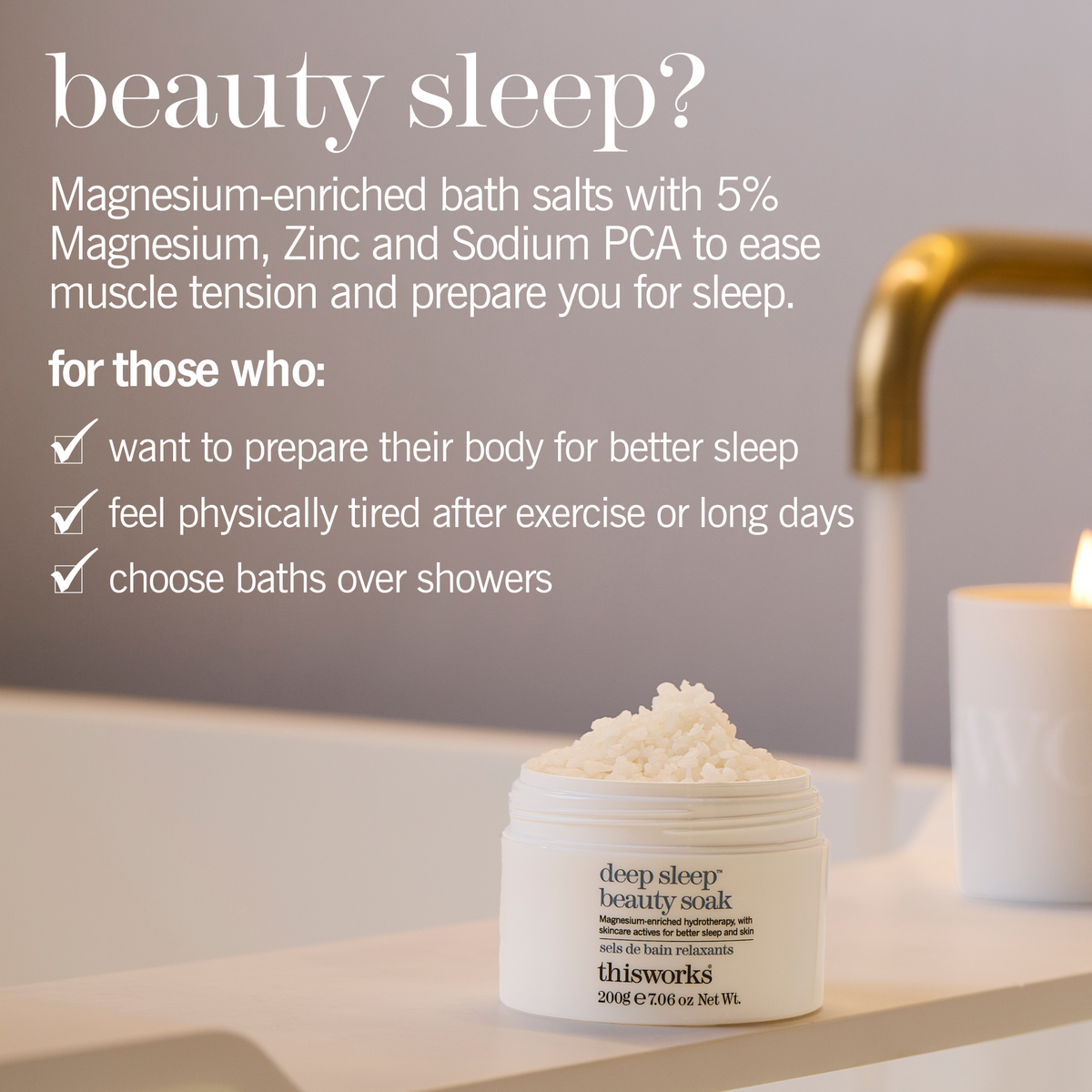 A white jar of This Works Deep Sleep Beauty Soak sits open on a bathroom counter, with a candle, gold faucet, and soft gray wall in the background. White text on the left describes the bath salts' benefits for sleep.